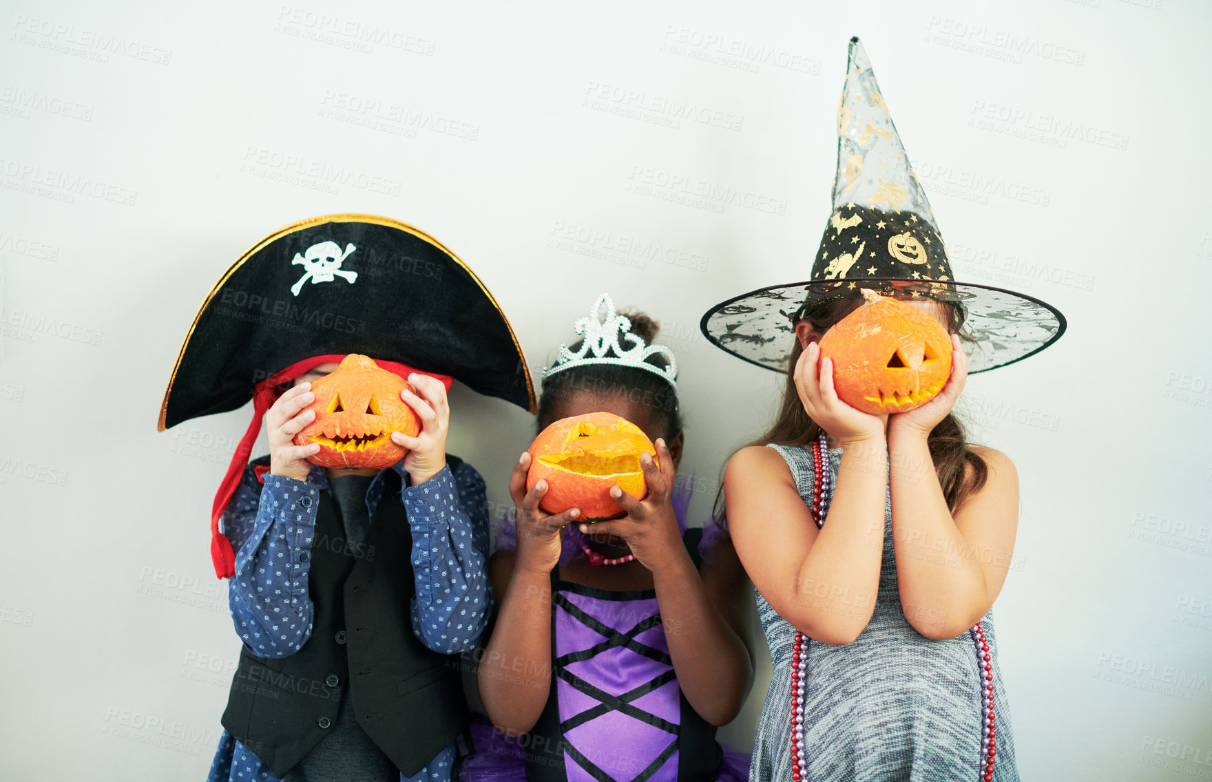 Buy stock photo Shot of a group of unrecognizable little children covering their faces with pumpkins at a party
