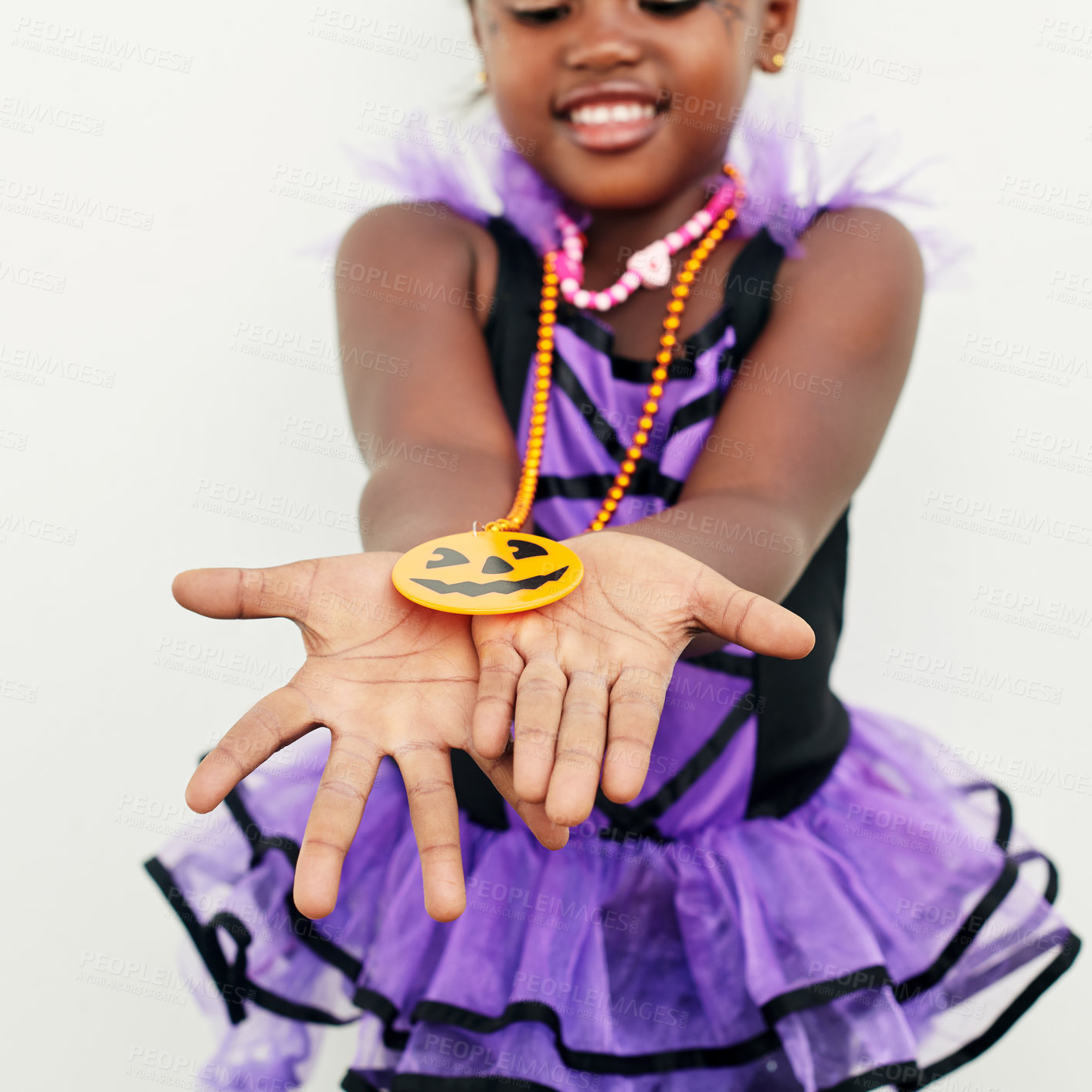 Buy stock photo Shot of a little girl holding a jack o lantern pendant in her hands against a white background