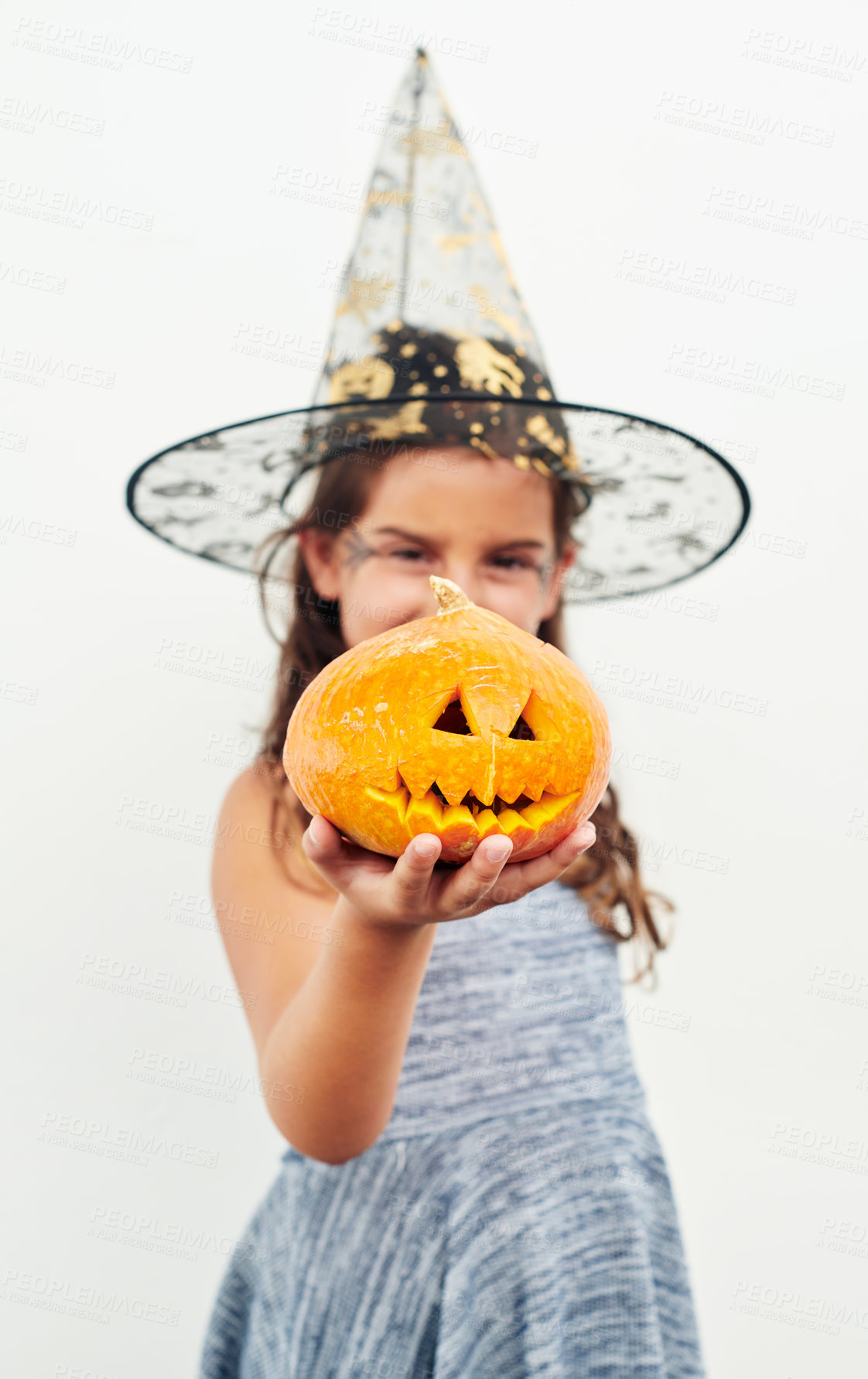 Buy stock photo Shot of a little girl wearing a witch hat while holding a jack o lantern against a white background