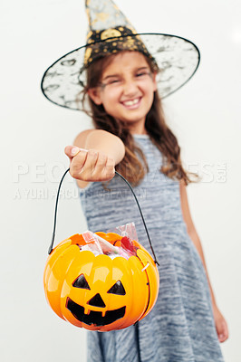Buy stock photo Shot of a little girl wearing a witch hat while holding a jack o lantern against a white background
