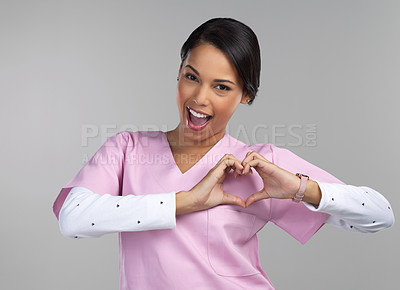 Buy stock photo Cropped portrait of an attractive young female healthcare worker gesturing a heart shape with her hands in studio against a grey background