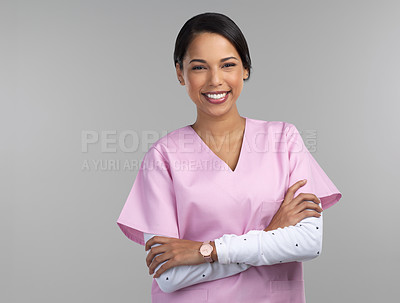 Buy stock photo Cropped portrait of an attractive young female healthcare worker standing with her arms crossed in studio against a grey background