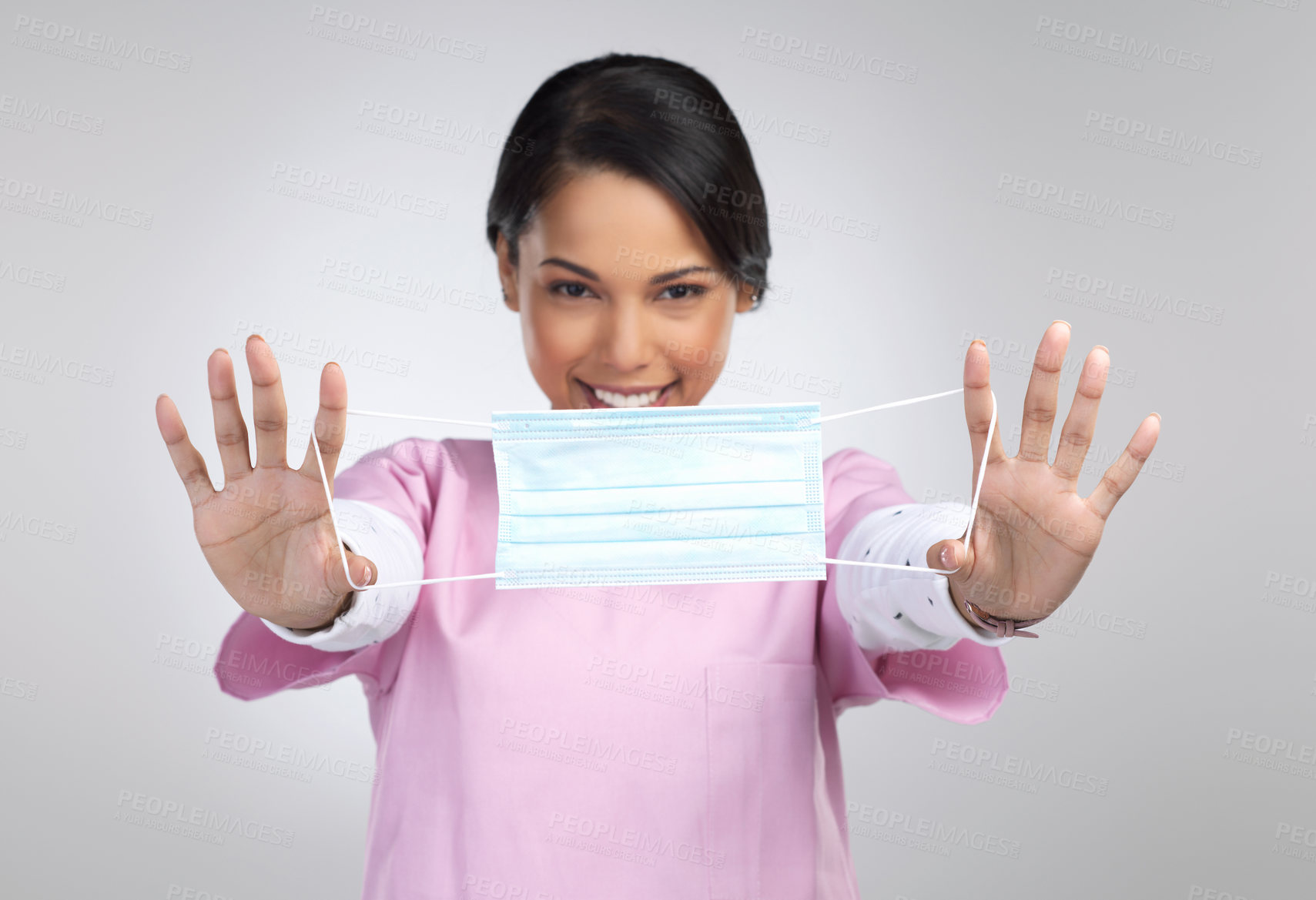 Buy stock photo Cropped portrait of an attractive young female healthcare worker holding up a mask in studio against a grey background