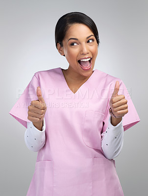 Buy stock photo Cropped shot of an attractive young female healthcare worker gesturing thumbs up in studio against a grey background