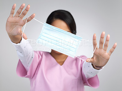 Buy stock photo Cropped portrait of an unrecognizable young female healthcare worker holding up a mask in studio against a grey background