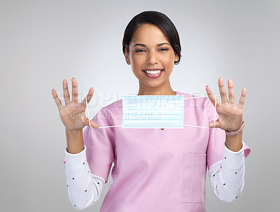 Buy stock photo Cropped portrait of an attractive young female healthcare worker holding up a mask in studio against a grey background