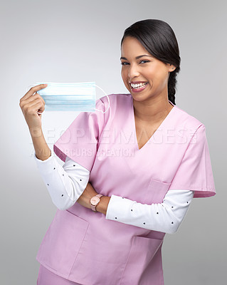 Buy stock photo Cropped portrait of an attractive young female healthcare worker holding up a mask in studio against a grey background