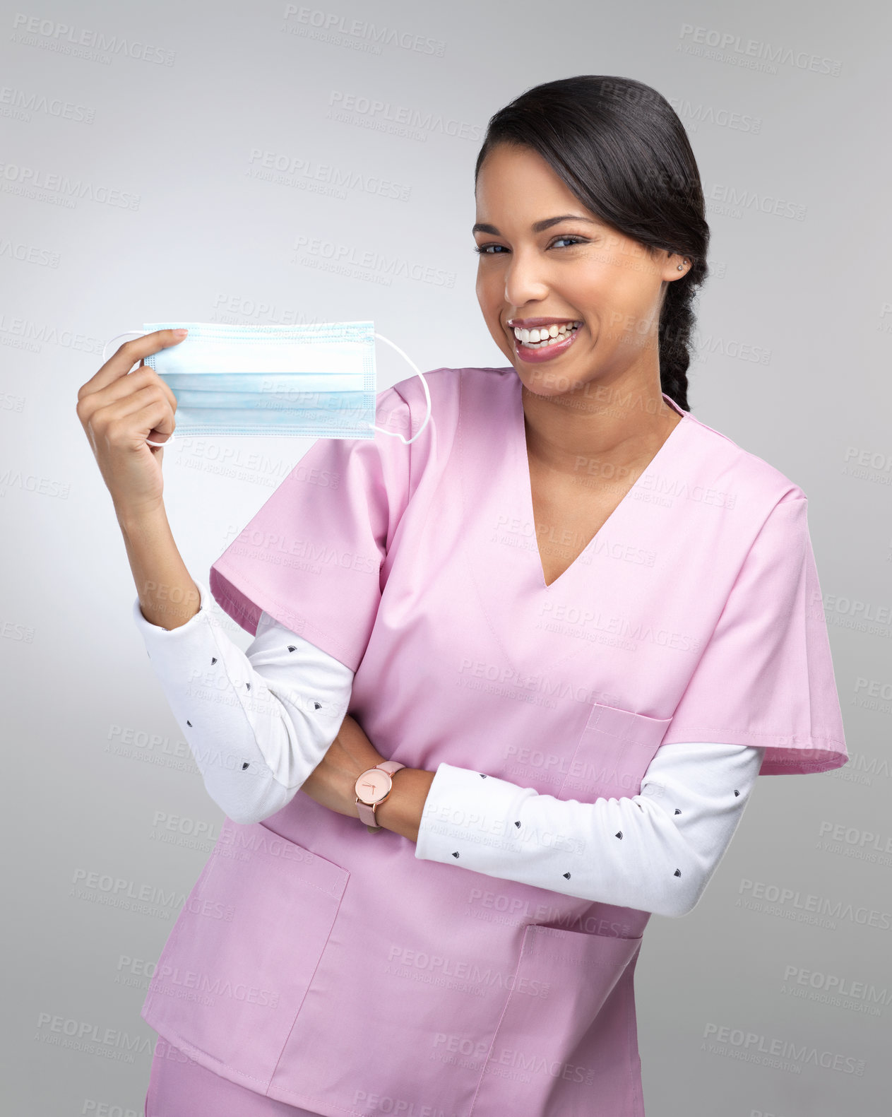 Buy stock photo Cropped portrait of an attractive young female healthcare worker holding up a mask in studio against a grey background