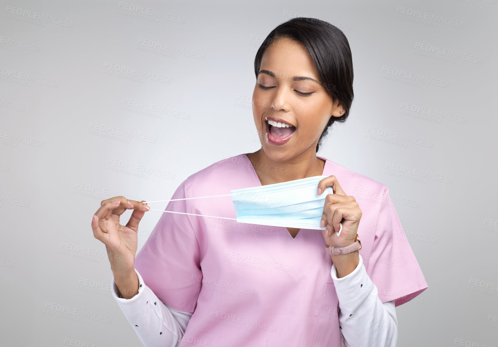 Buy stock photo Cropped shot of an attractive young female healthcare worker holding up a mask in studio against a grey background