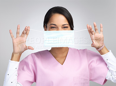 Buy stock photo Cropped portrait of an attractive young female healthcare worker holding up a mask in studio against a grey background