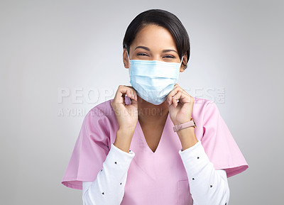 Buy stock photo Cropped portrait of an attractive young female healthcare worker wearing a mask and standing in studio against a grey background