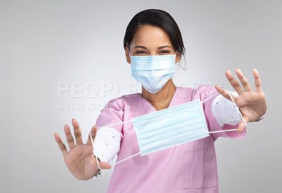 Buy stock photo Cropped portrait of an attractive young female healthcare worker holding up a mask in studio against a grey background