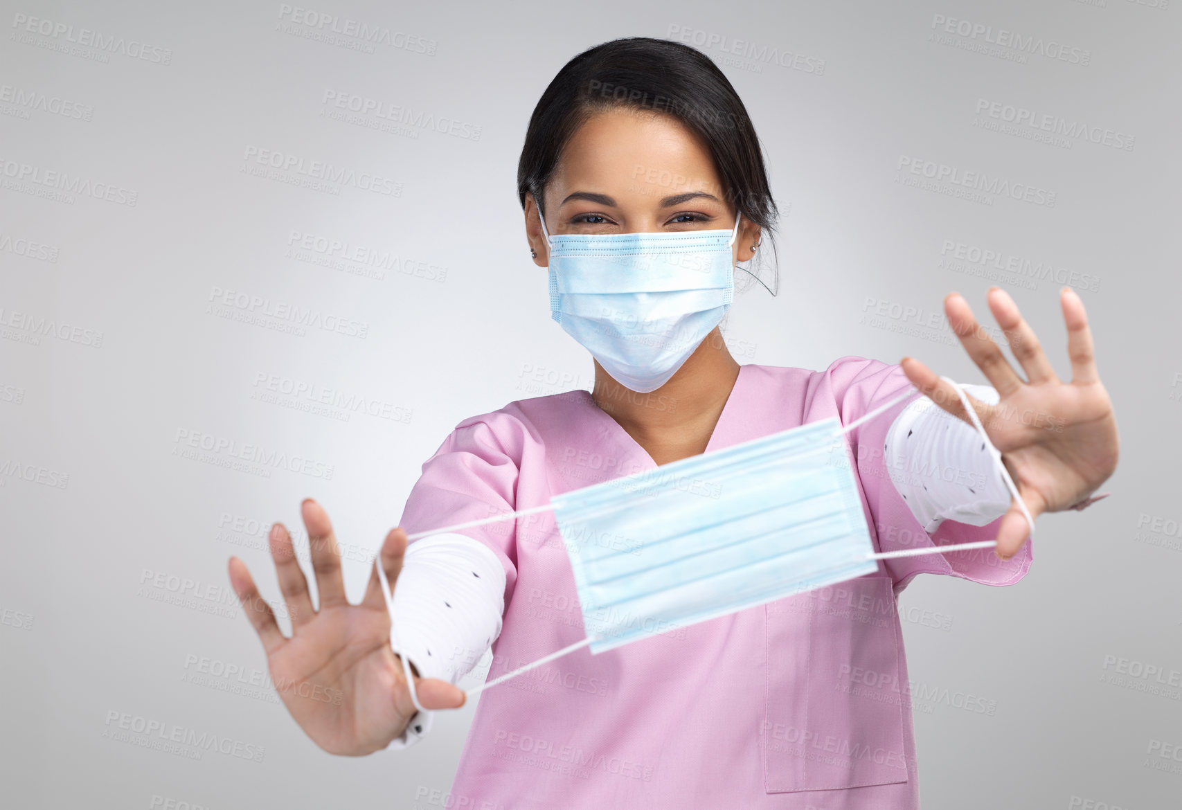 Buy stock photo Cropped portrait of an attractive young female healthcare worker holding up a mask in studio against a grey background