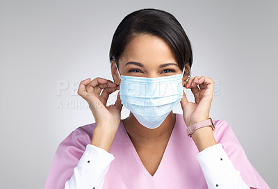 Buy stock photo Cropped portrait of an attractive young female healthcare worker wearing a mask and standing in studio against a grey background