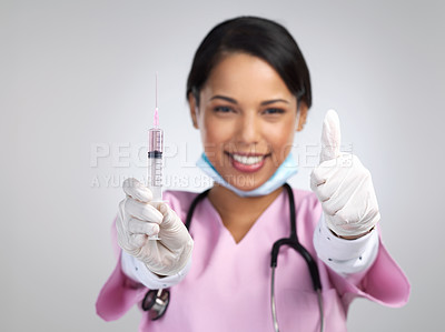 Buy stock photo Cropped portrait of an attractive young female healthcare working holding up a syringe and gesturing thumbs up in studio against a grey background