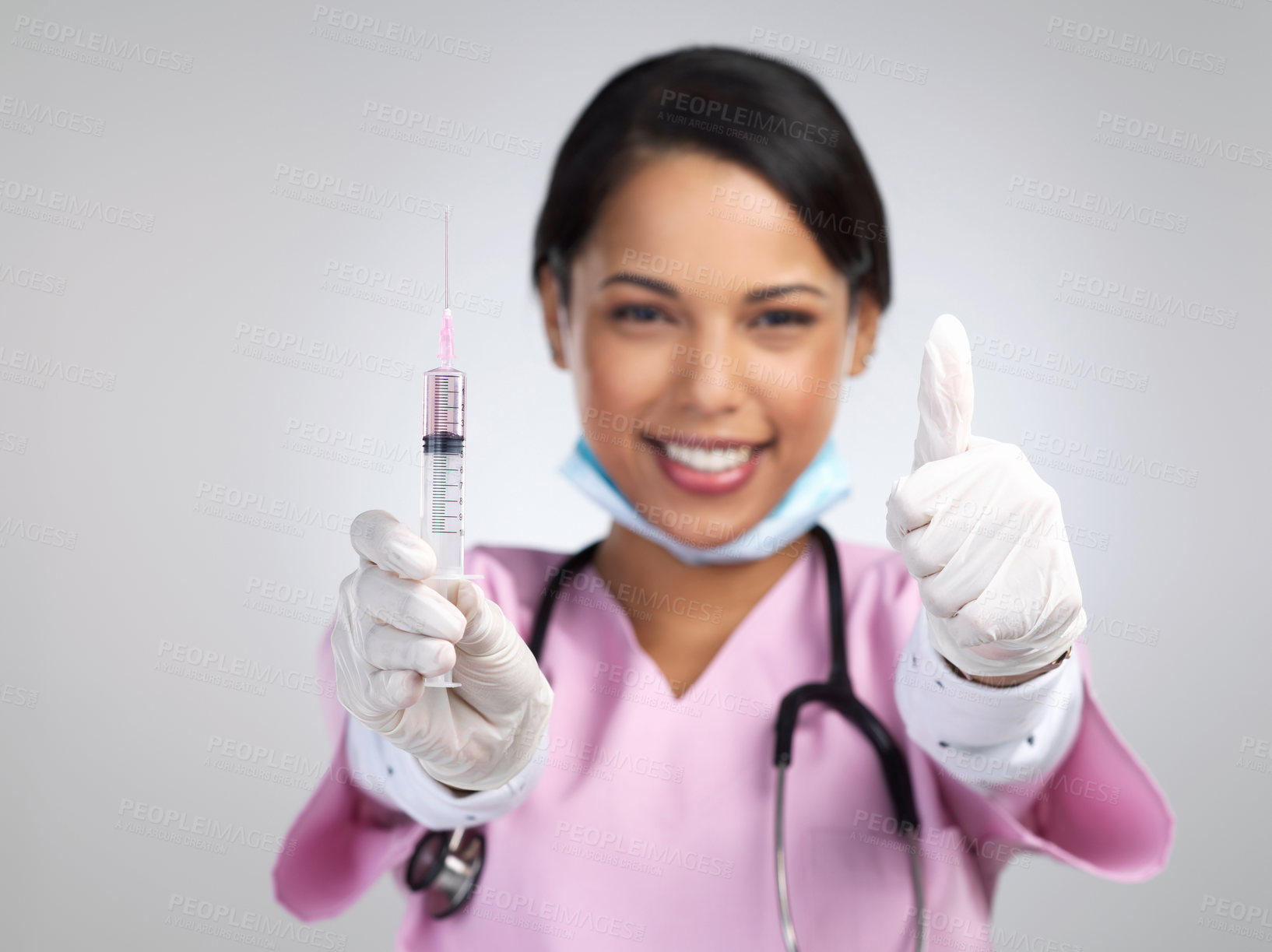 Buy stock photo Cropped portrait of an attractive young female healthcare working holding up a syringe and gesturing thumbs up in studio against a grey background