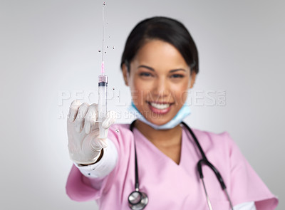 Buy stock photo Cropped portrait of an attractive young female healthcare working holding up a syringe in studio against a grey background