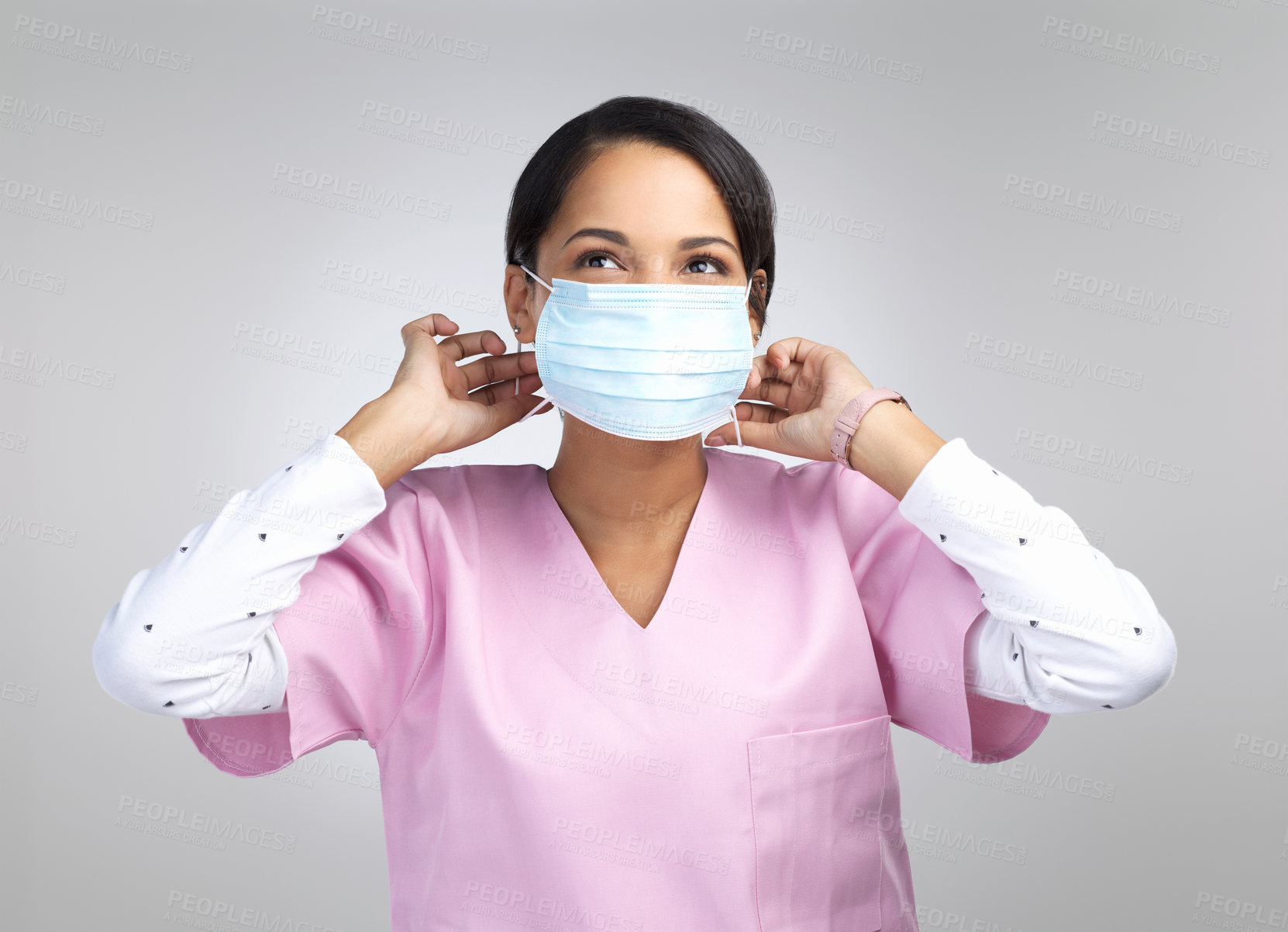 Buy stock photo Cropped shot of an attractive young female healthcare worker wearing a mask and looking thoughtful in studio against a grey background