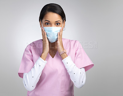 Buy stock photo Cropped portrait of an attractive young female healthcare worker wearing a mask and looking shocked in studio against a grey background