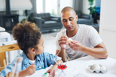 Buy stock photo Shot of a man painting eggs with his daughter at home