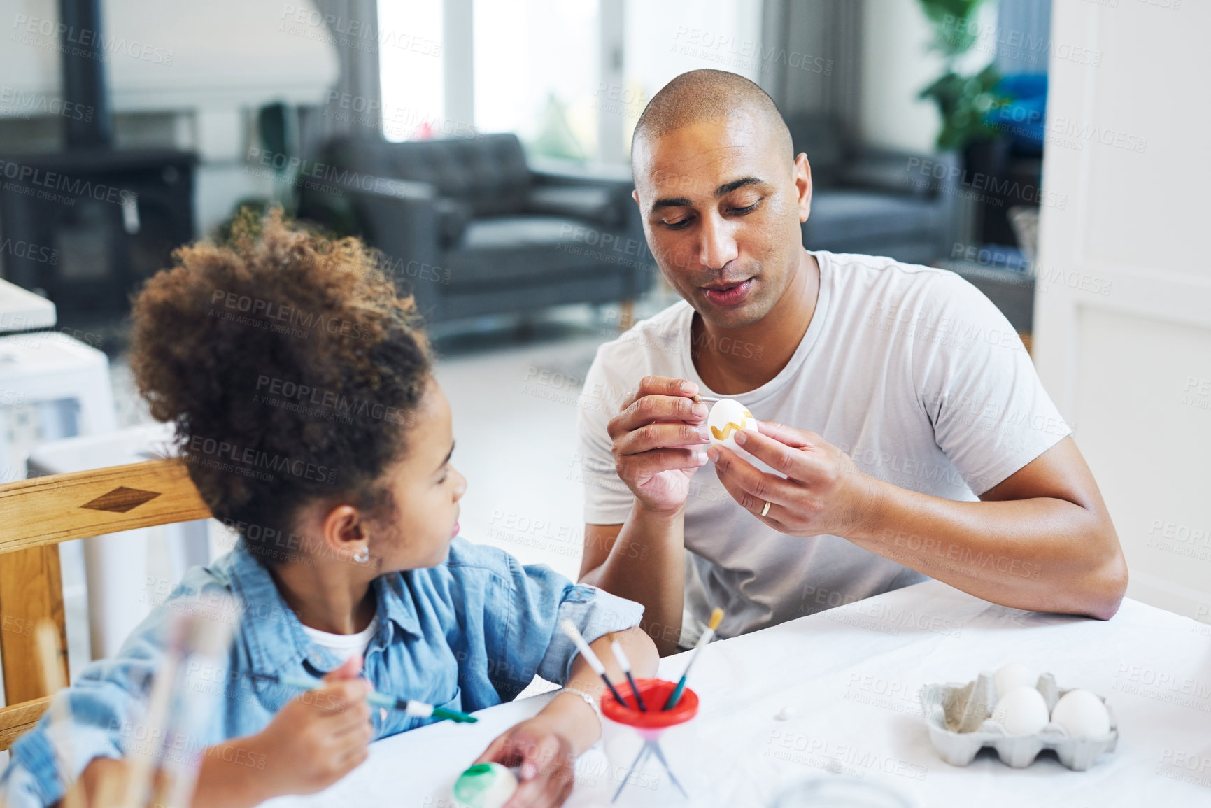 Buy stock photo Shot of a man painting eggs with his daughter at home