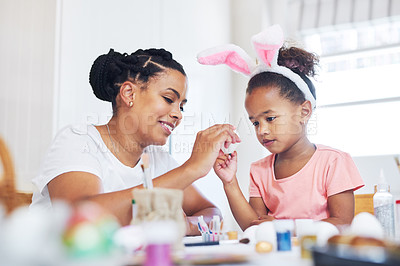 Buy stock photo Shot of a female painting eggs with her daughter at home