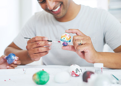 Buy stock photo Shot of a young man painting eggs at home