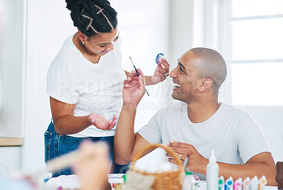 Buy stock photo Shot of a young couple painting eggs at home