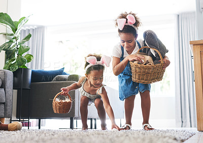 Buy stock photo Shot of two sisters during a easter hunt at home