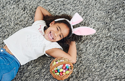 Buy stock photo Shot of a young girl laying on the floor with a basket of Easter eggs at home