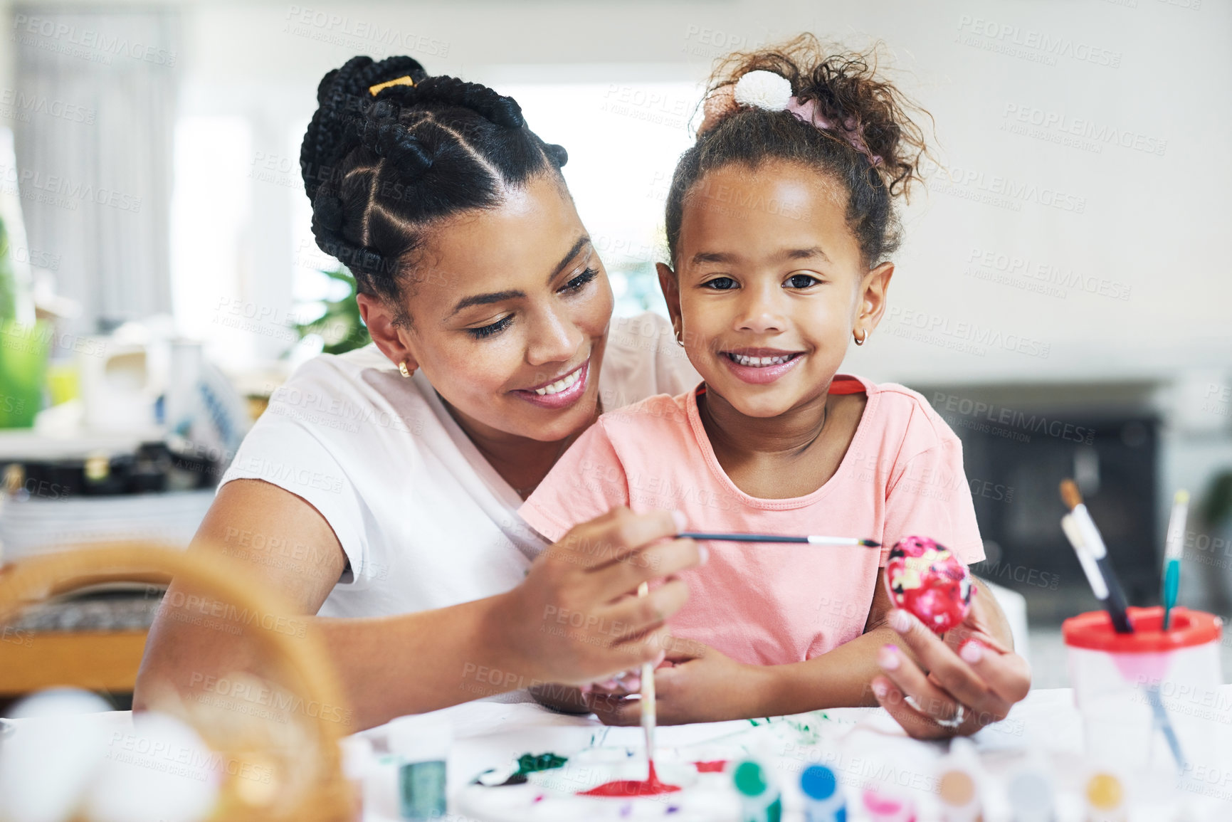 Buy stock photo Shot of a female painting eggs with her daughter at home