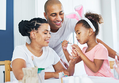 Buy stock photo Shot of a mother and father painting eggs with their daughter at home