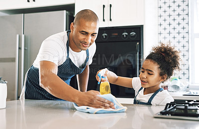 Buy stock photo Shot of a young man cleaning a surface with a child at home