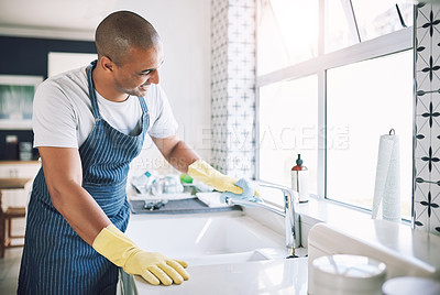 Buy stock photo Shot of a young man cleaning a kitchen at home