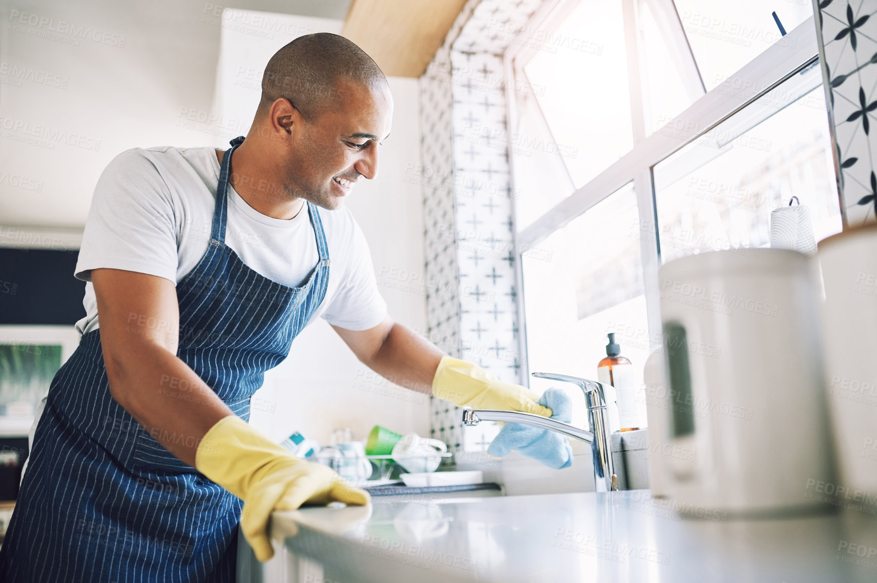 Buy stock photo Shot of a young man cleaning a kitchen at home