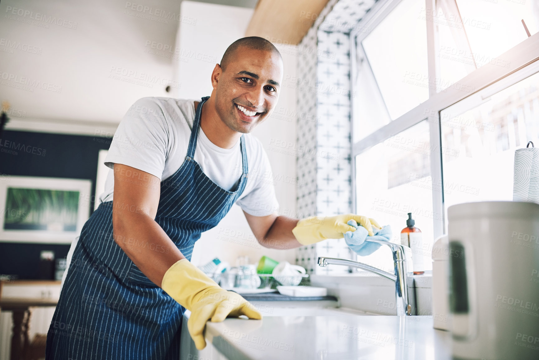 Buy stock photo Shot of a young man cleaning a kitchen at home