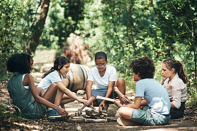 Buy stock photo Shot of a group of teenagers building a pile of wood at summer camp