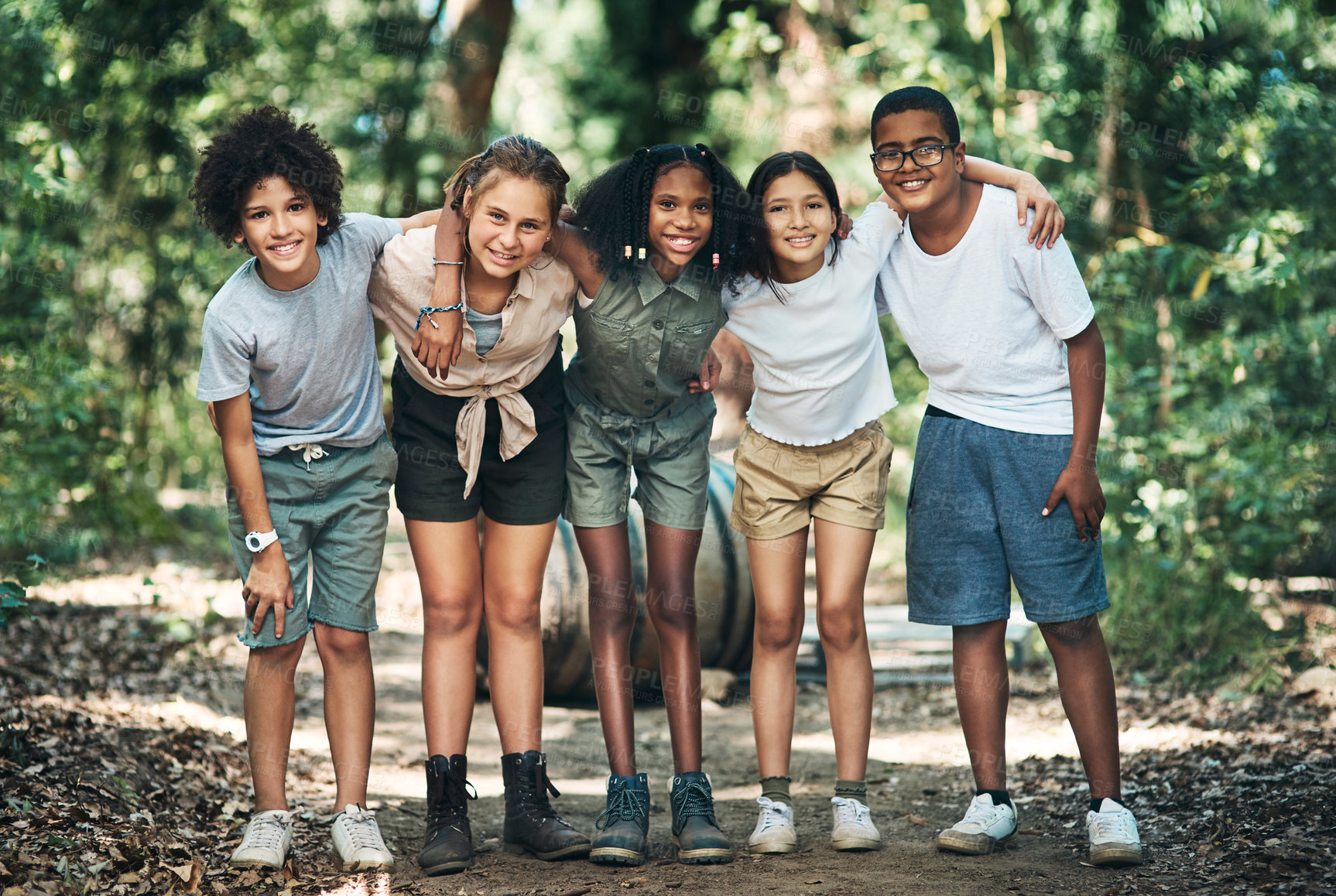 Buy stock photo Shot of a group of teenagers embracing in nature at summer camp