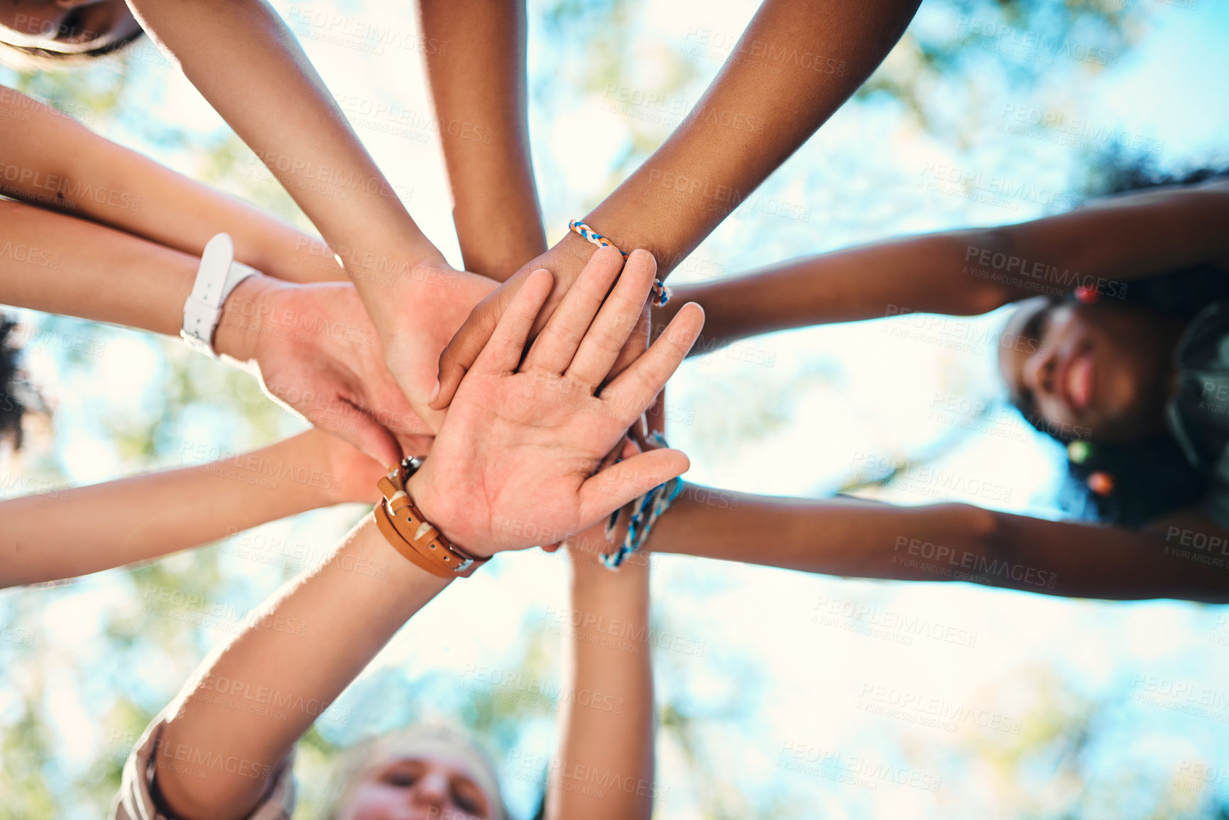 Buy stock photo Shot of a group of teenagers standing in a circle and joining their hands in solidarity at summer camp