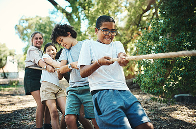 Buy stock photo Shot of a group of teenagers playing a game of tug of war at summer camp