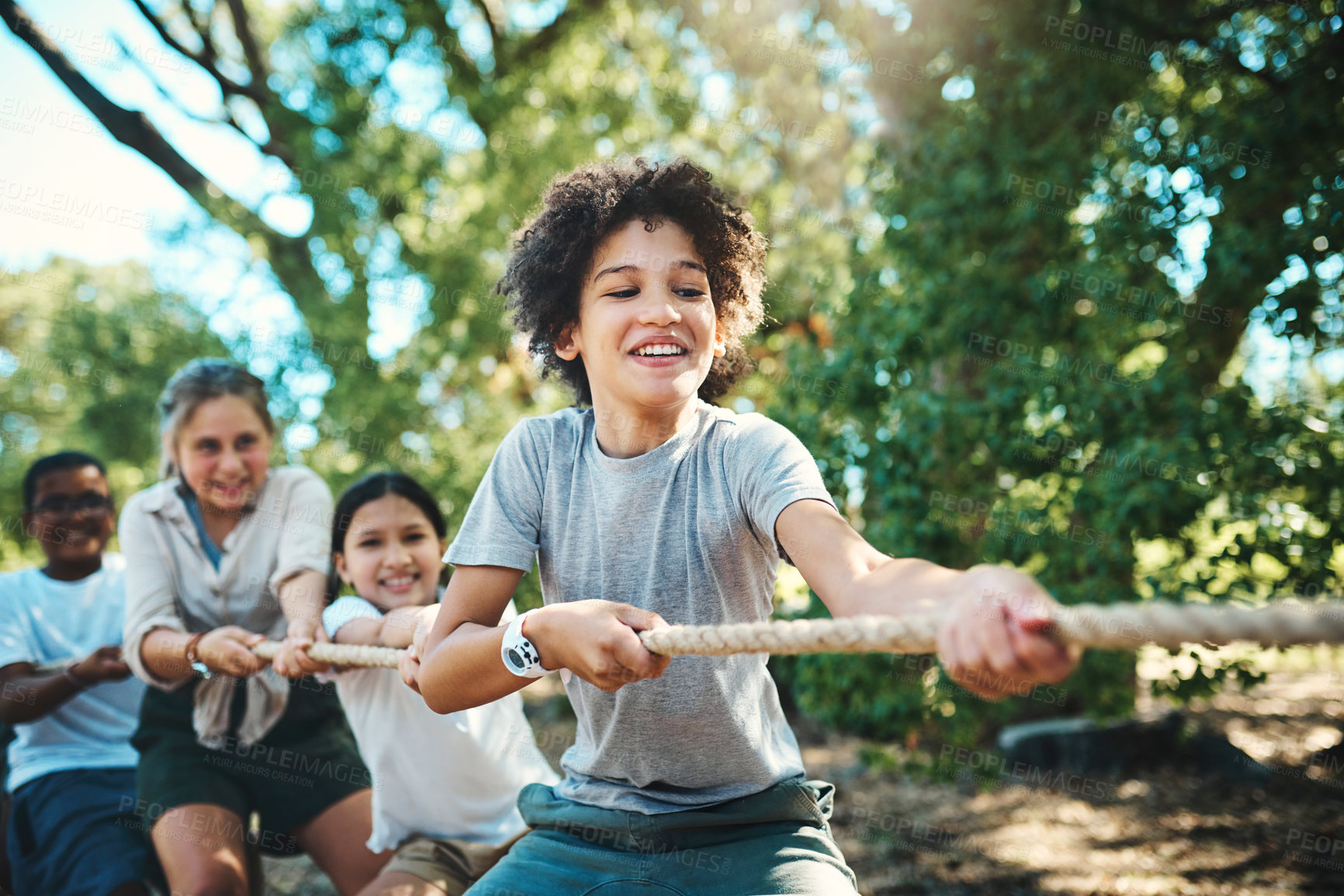 Buy stock photo Shot of a group of teenagers playing a game of tug of war at summer camp