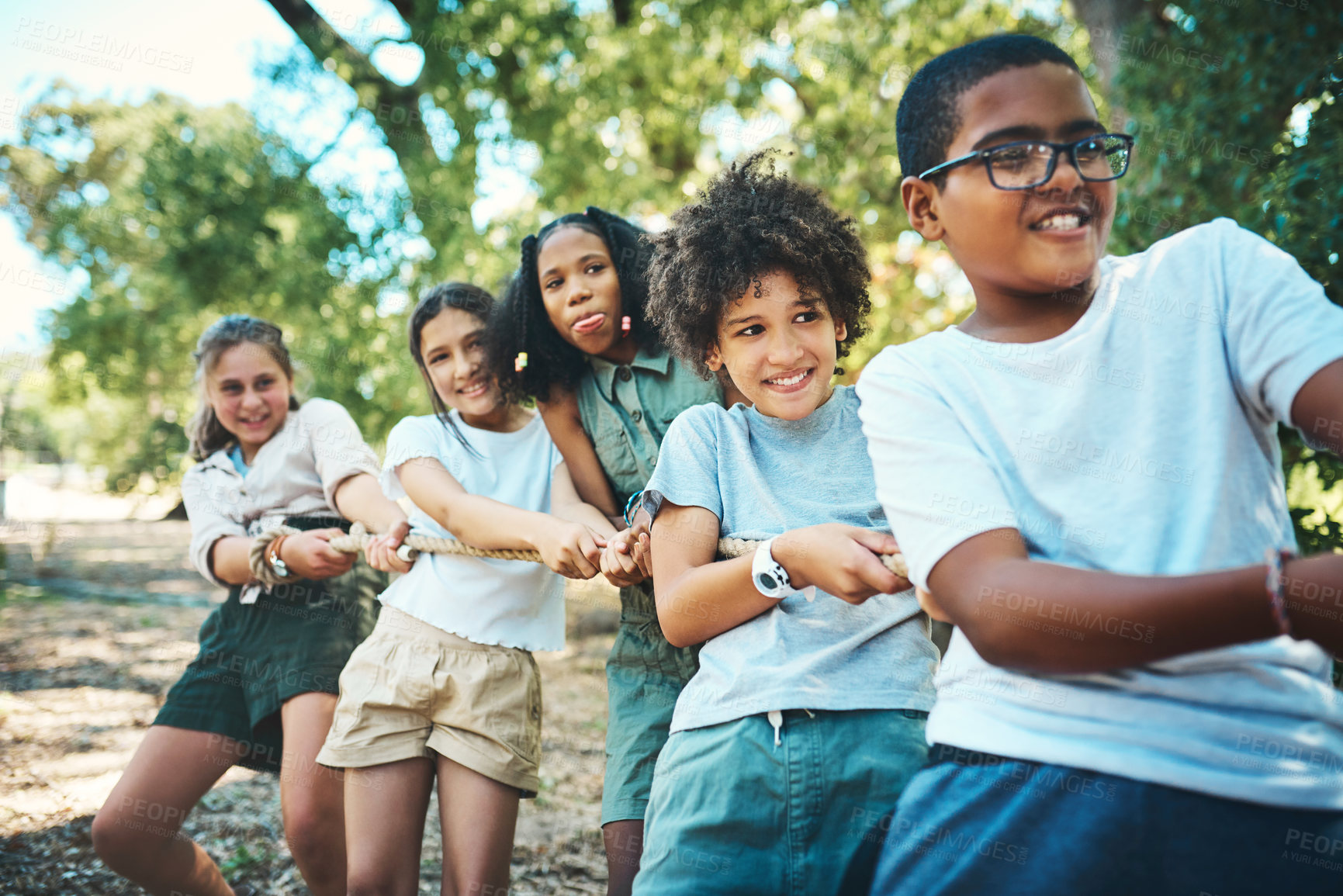 Buy stock photo Shot of a group of teenagers playing a game of tug of war at summer camp