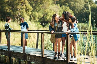 Buy stock photo Shot of a group of teenagers standing on a bridge in nature at summer camp