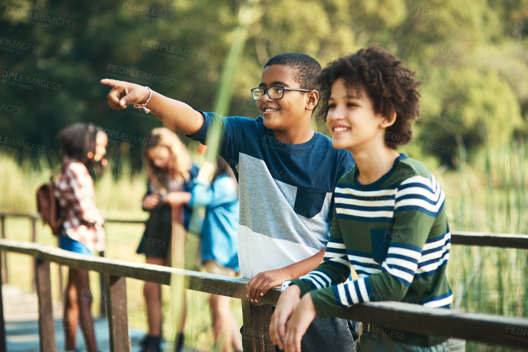 Buy stock photo Shot of two teenage boys standing on a bridge in nature at summer camp