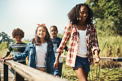 Buy stock photo Shot of a group of teenagers walking across a bridge in nature at summer camp