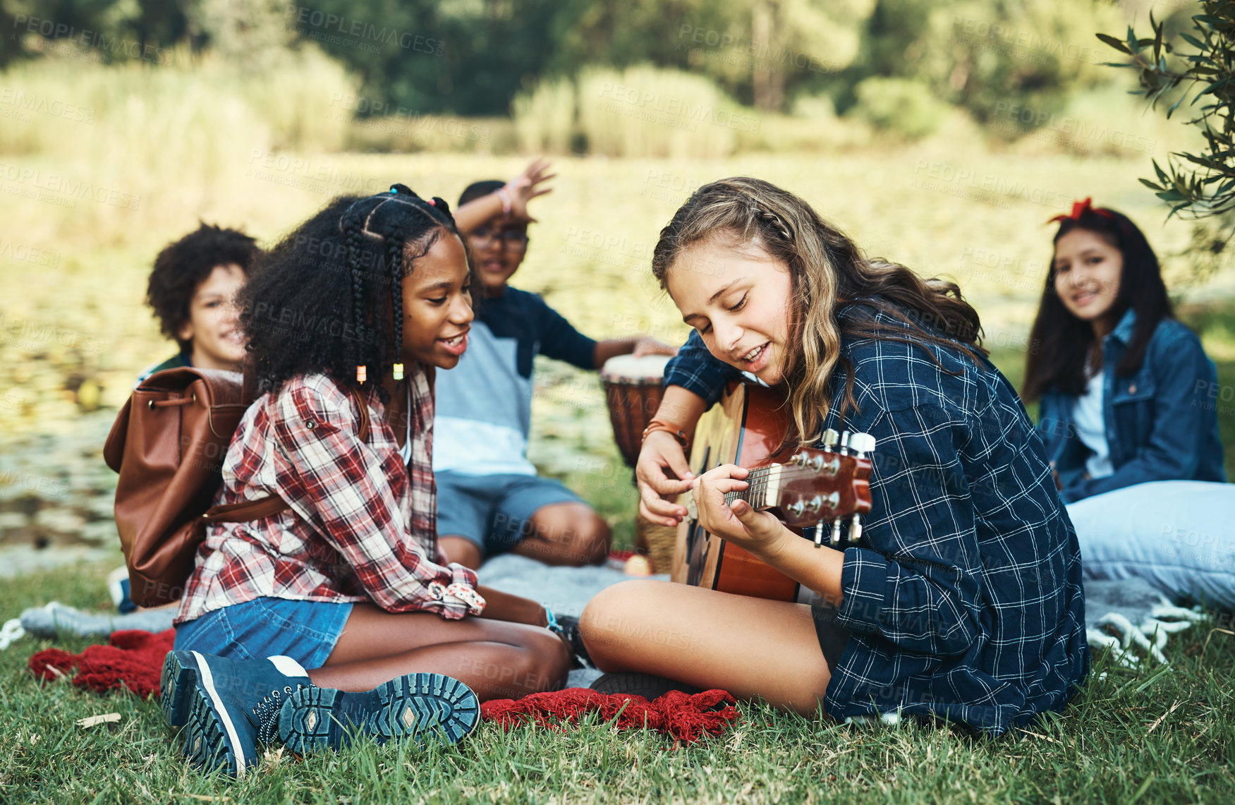 Buy stock photo Shot of a group of teenagers playing musical instruments in nature at summer camp