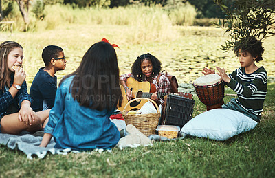 Buy stock photo Shot of a group of teenagers playing musical instruments in nature at summer camp