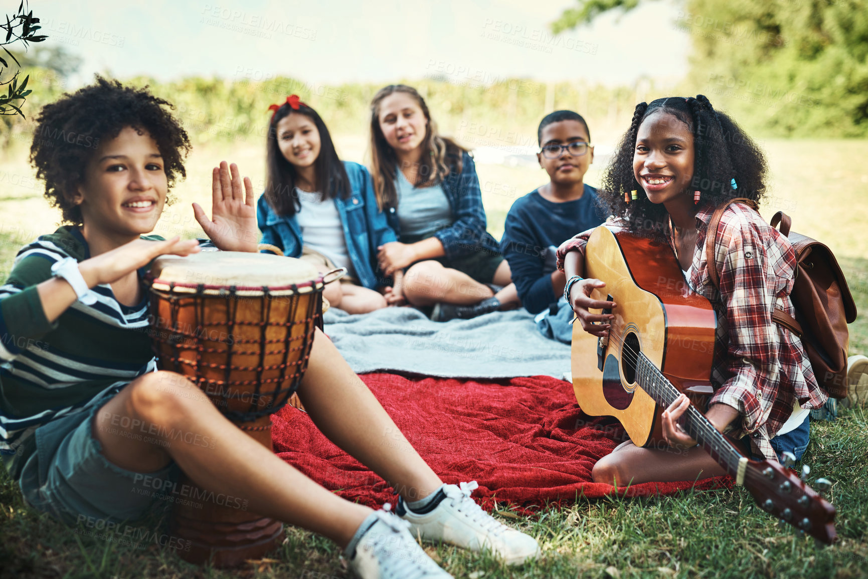 Buy stock photo Shot of a group of teenagers playing musical instruments in nature at summer camp