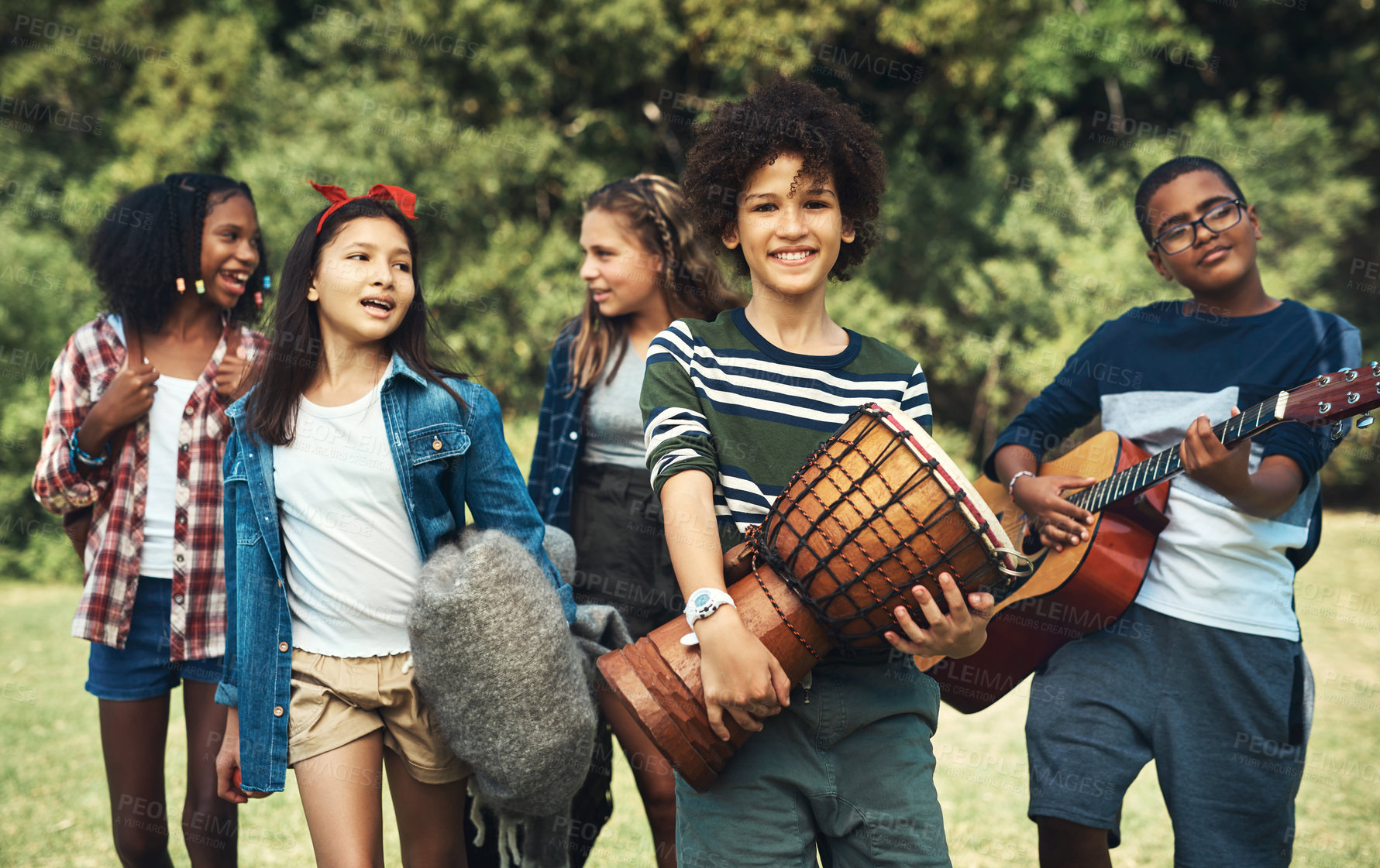 Buy stock photo Shot of a group of teenagers playing musical instruments in nature at summer camp