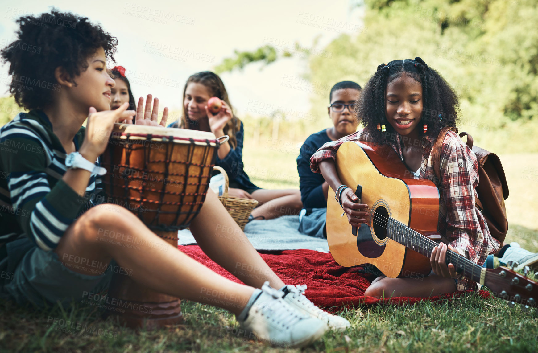 Buy stock photo Shot of a group of teenagers playing musical instruments in nature at summer camp